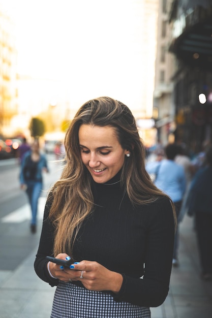 Jonge blanke vrouw met behulp van een smartphone op de Gran Via Avenue in Madrid, Spanje.