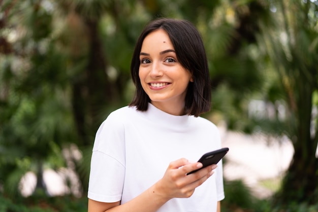 Jonge blanke vrouw met behulp van een telefoon buitenshuis