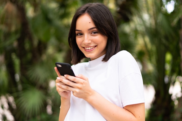 Jonge blanke vrouw met behulp van een telefoon buitenshuis