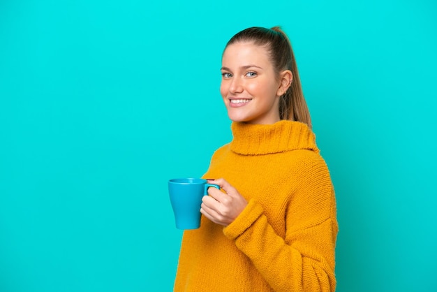 Jonge blanke vrouw met beker geïsoleerd op een blauwe achtergrond die veel lacht