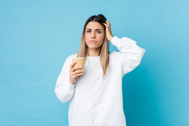 Jonge blanke vrouw met een afhaalmaaltijden koffie wordt geschokt, ze heeft belangrijke vergadering onthouden.