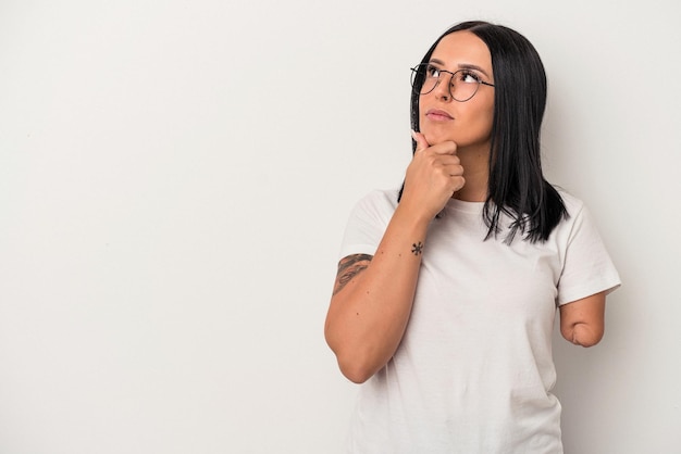 Jonge blanke vrouw met één arm geïsoleerd op een witte achtergrond zijwaarts kijkend met twijfelachtige en sceptische uitdrukking.