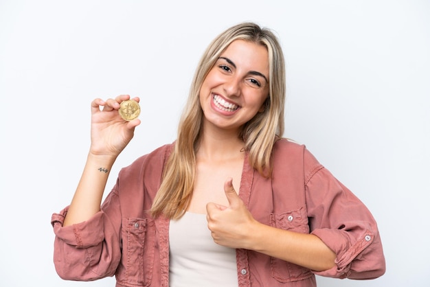 Jonge blanke vrouw met een Bitcoin geïsoleerd op een witte achtergrond met duimen omhoog omdat er iets goeds is gebeurd