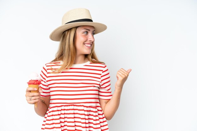 Jonge blanke vrouw met een cornet-ijs geïsoleerd op een witte achtergrond wijzend naar de zijkant om een product te presenteren