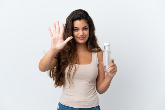 Jonge blanke vrouw met een fles water geïsoleerd op een witte achtergrond die vijf met vingers telt