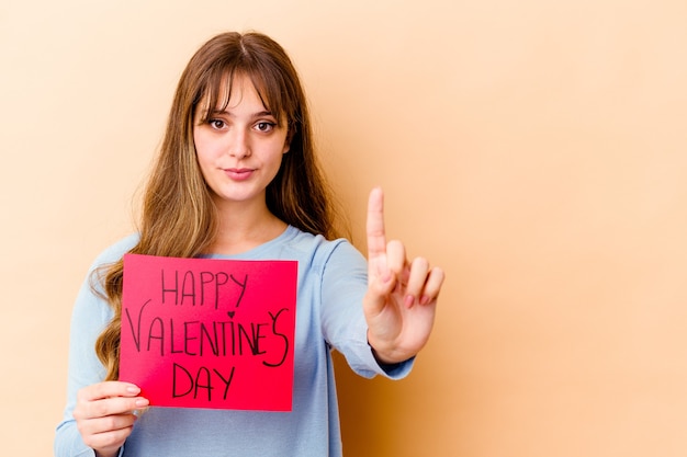 Jonge blanke vrouw met een gelukkige Valentijnsdag geïsoleerd met nummer één met vinger.
