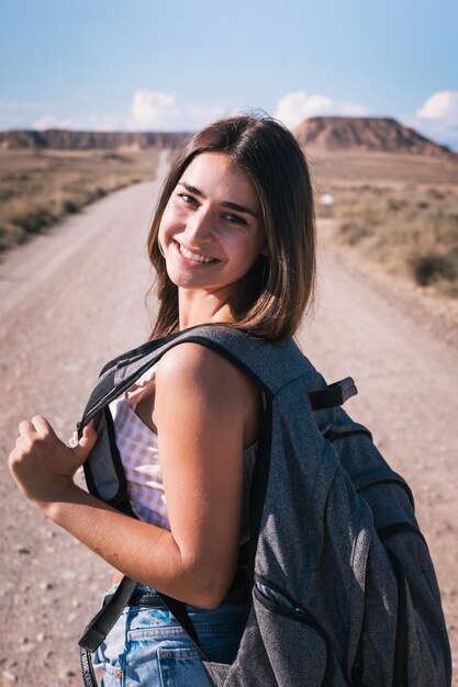 Jonge blanke vrouw met een grijze rugzak wandelen in het midden van een dessert in bardenas, navarra, baskenland.