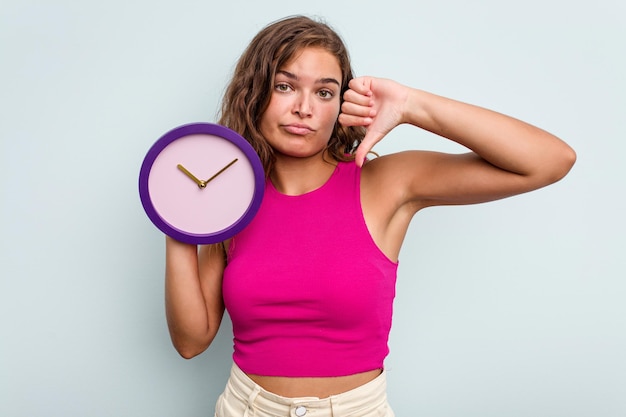 Foto jonge blanke vrouw met een horloge geïsoleerd op blauwe achtergrond met een afkeer gebaar