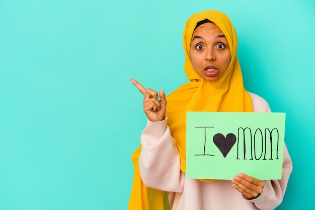 Jonge blanke vrouw met een ik hou van moeder geïsoleerd op roze muur wijzend naar de zijkant