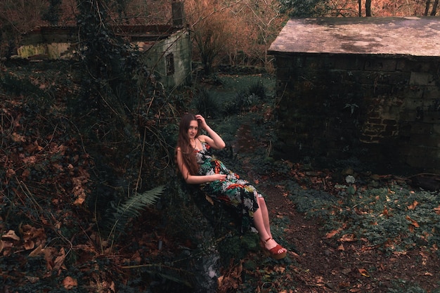 Jonge blanke vrouw met een kleurrijke jurk midden in het bos naast een riviertje