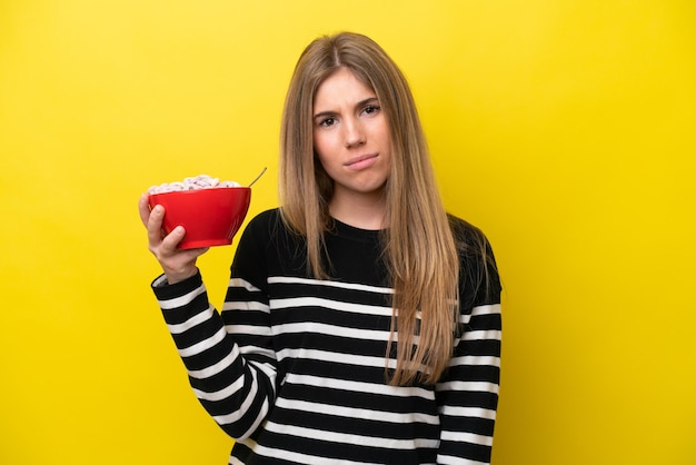 Jonge blanke vrouw met een kom granen geïsoleerd op een gele achtergrond met droevige uitdrukking