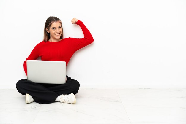 Jonge blanke vrouw met een laptop zittend op de vloer doet sterk gebaar