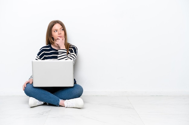 Jonge blanke vrouw met een laptop zittend op de vloer