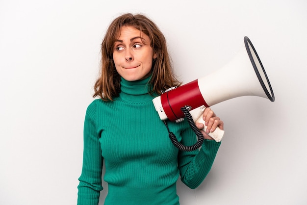 Foto jonge blanke vrouw met een megafoon geïsoleerd op een witte achtergrond verward voelt zich twijfelachtig en onzeker