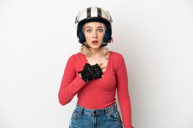 Jonge blanke vrouw met een motorhelm geïsoleerd op een witte achtergrond verrast en geschokt terwijl ze naar rechts kijkt