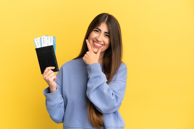 Jonge blanke vrouw met een paspoort geïsoleerd op een gele achtergrond gelukkig en glimlachend