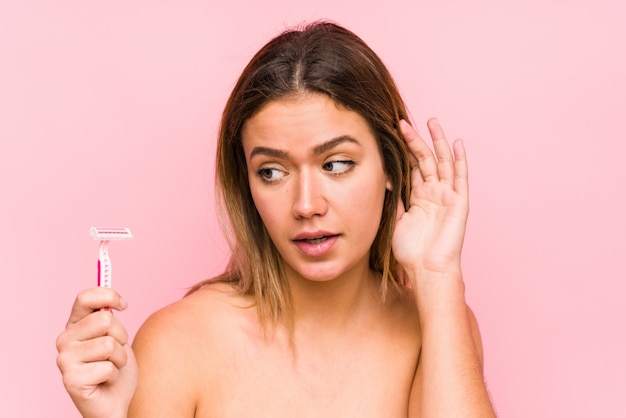 Jonge blanke vrouw met een scheermesje Jonge blanke vrouw met een haarborstel probeert te luisteren naar een roddel