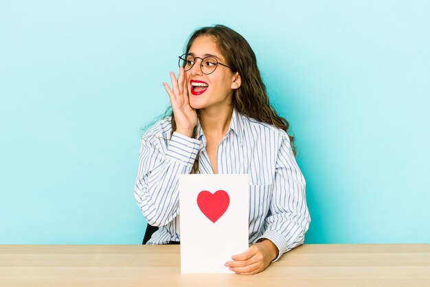 Jonge blanke vrouw met een Valentijnsdag kaart geïsoleerd schreeuwen en palm in de buurt van geopende mond te houden.