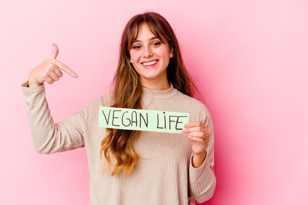 Foto jonge blanke vrouw met een veganistisch leven plakkaat geïsoleerde persoon met de hand wijzend naar een shirt kopie ruimte, trots en zelfverzekerd