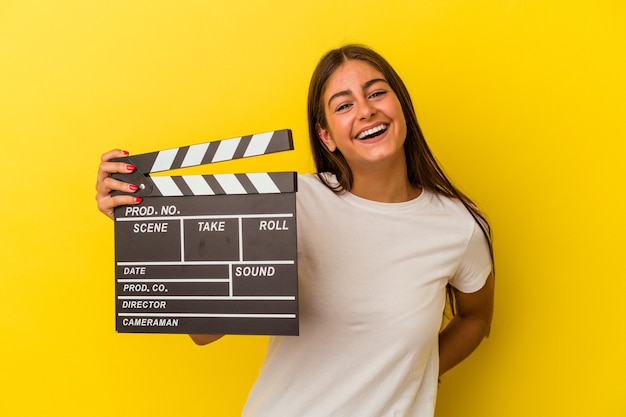 Jonge blanke vrouw met Filmklapper geïsoleerd op een witte muur lachen en plezier hebben.