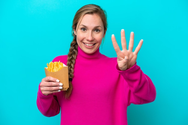 Jonge blanke vrouw met gebakken chips geïsoleerd op blauwe achtergrond blij en vier tellen met vingers