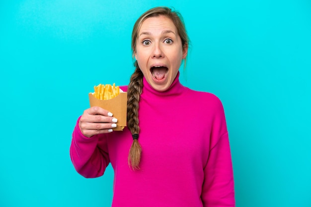 Jonge blanke vrouw met gebakken chips geïsoleerd op blauwe achtergrond met verrassende gezichtsuitdrukking