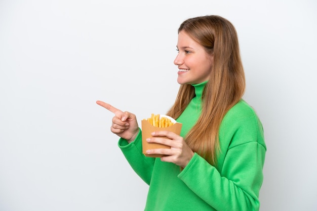 Jonge blanke vrouw met gebakken chips geïsoleerd op een witte achtergrond, wijzend naar de zijkant om een product te presenteren