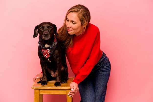 Jonge blanke vrouw met haar hond geïsoleerd op roze background