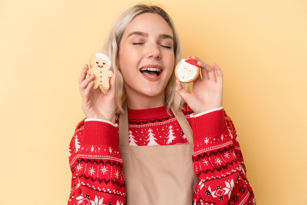 Jonge blanke vrouw met kerstkoekjes geïsoleerd op gele achtergrond