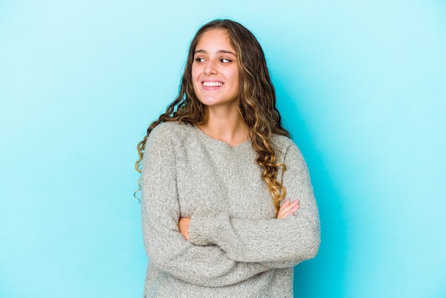 Jonge blanke vrouw met krullend haar geïsoleerd glimlachend vertrouwen met gekruiste armen.