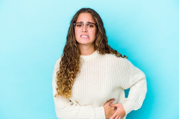 Jonge blanke vrouw met krullend haar geïsoleerd met leverpijn, buikpijn.