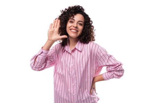 Jonge blanke vrouw met krullend zwart haar glimlachend op een witte achtergrond met kopieerruimte