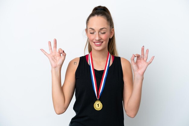 Jonge blanke vrouw met medailles geïsoleerd op een witte achtergrond in zen pose