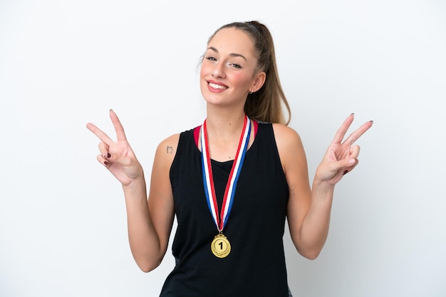 Jonge blanke vrouw met medailles geïsoleerd op een witte achtergrond met overwinningsteken met beide handen