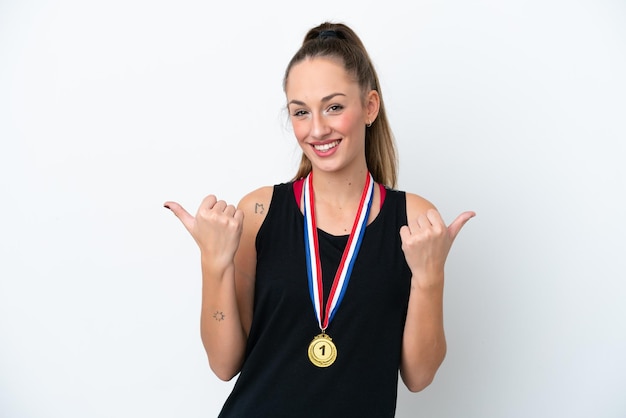 Jonge blanke vrouw met medailles geïsoleerd op een witte achtergrond met thumbs up gebaar en lachend