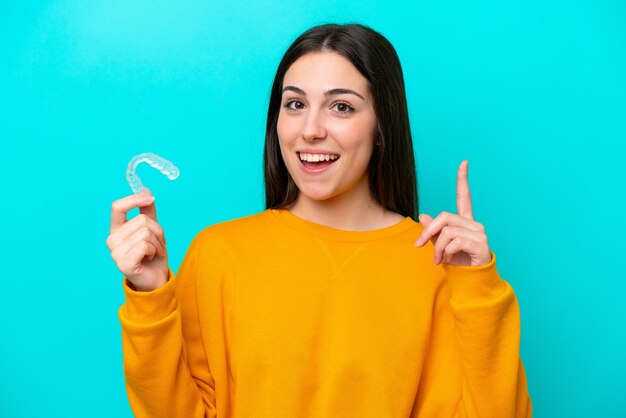 Jonge blanke vrouw met onzichtbare beugels geïsoleerd op een blauwe achtergrond die een geweldig idee benadrukt