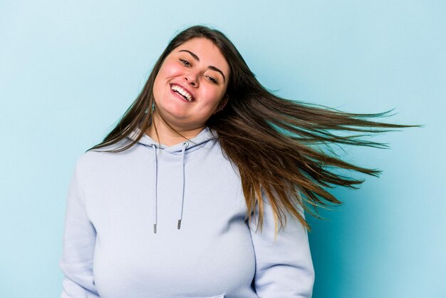 Jonge blanke vrouw met overgewicht geïsoleerd op blauwe achtergrond dansen en plezier