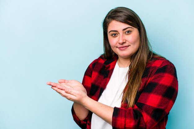 Jonge blanke vrouw met overgewicht geïsoleerd op blauwe achtergrond met een kopie ruimte op een palm