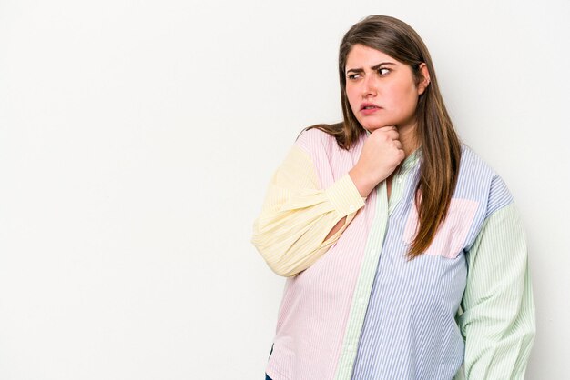 Jonge blanke vrouw met overgewicht geïsoleerd op een witte achtergrond aanraken van de achterkant van het hoofd, denken en het maken van een keuze.