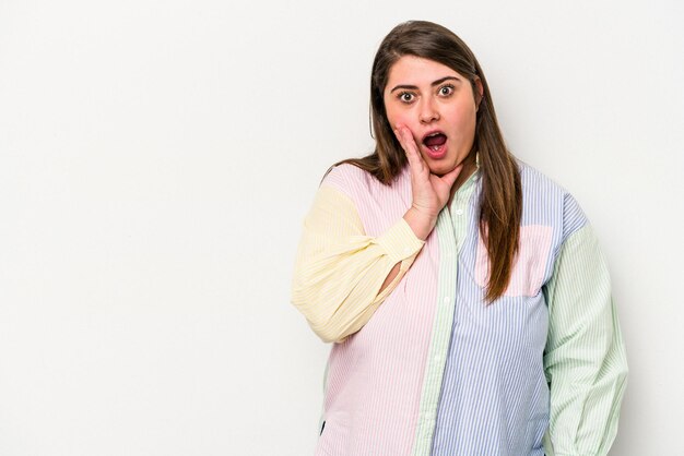 Jonge blanke vrouw met overgewicht geïsoleerd op een witte achtergrond schreeuwt luid houdt ogen open en handen gespannen