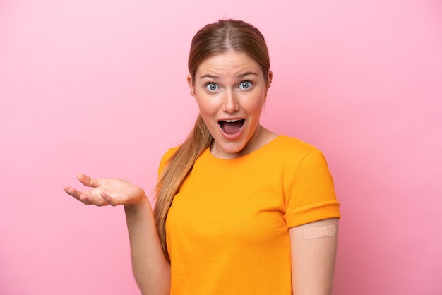 Jonge blanke vrouw met pleister geïsoleerd op roze achtergrond met geschokte gezichtsuitdrukking