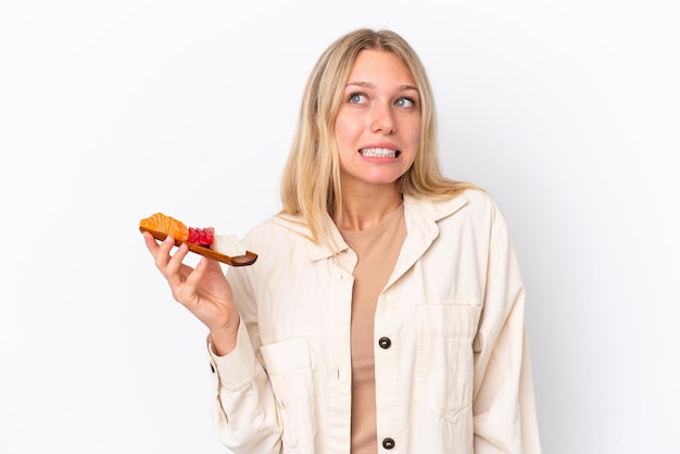 Jonge blanke vrouw met sashimi geïsoleerd op een witte achtergrond met twijfels en denken