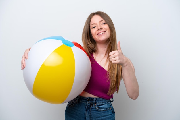 Jonge blanke vrouw met strandbal geïsoleerd op een witte achtergrond met duimen omhoog omdat er iets goeds is gebeurd