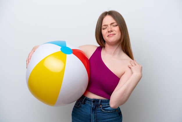 Jonge blanke vrouw met strandbal geïsoleerd op witte achtergrond die lijdt aan pijn in de schouder omdat ze zich heeft ingespannen