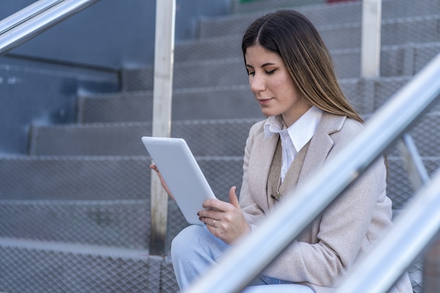 Jonge blanke vrouw met tablet zittend op een trap