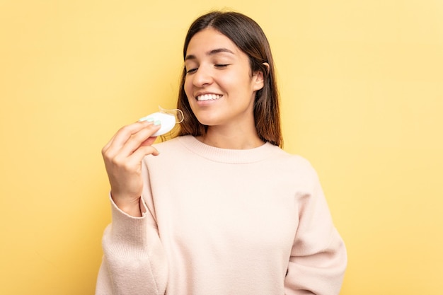 Jonge blanke vrouw met tandenbleekmiddel geïsoleerd op gele achtergrond