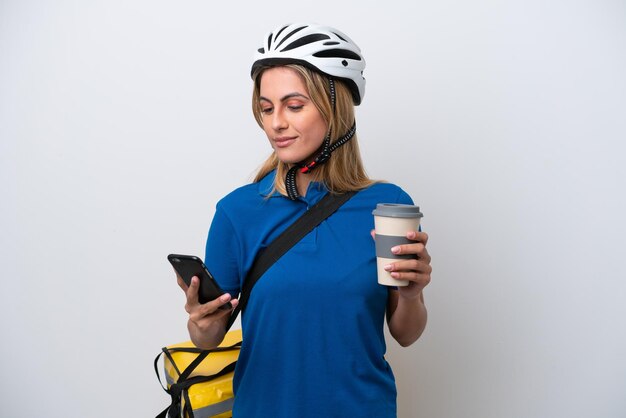 Jonge blanke vrouw met thermische rugzak geïsoleerd op een witte achtergrond met koffie om mee te nemen en een mobiel