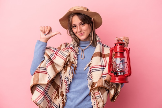 Jonge blanke vrouw met vintage lantaarn geïsoleerd op roze achtergrond voelt zich trots en zelfverzekerd, voorbeeld om te volgen.