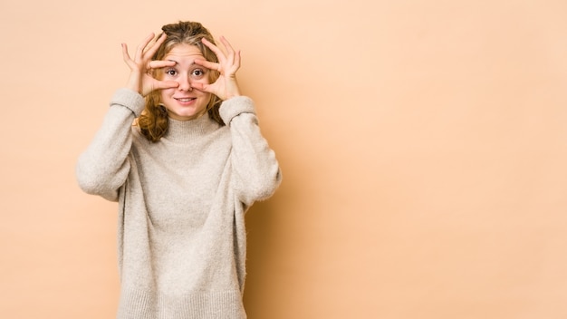 Jonge blanke vrouw op beige ogen geopend houden om een kans op succes te vinden.