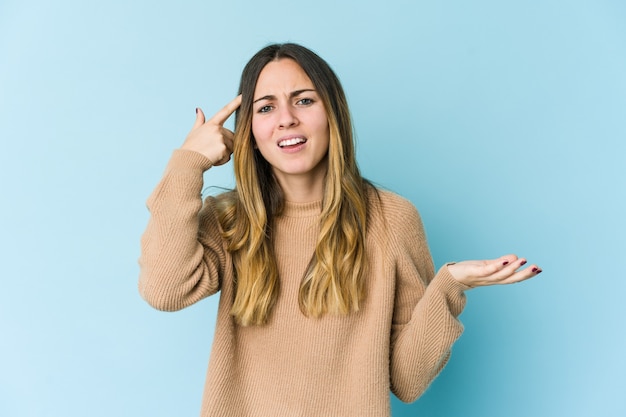 Jonge blanke vrouw op blauw met een gebaar van teleurstelling met wijsvinger.